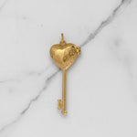 Gold key-shaped pendant on a marble background