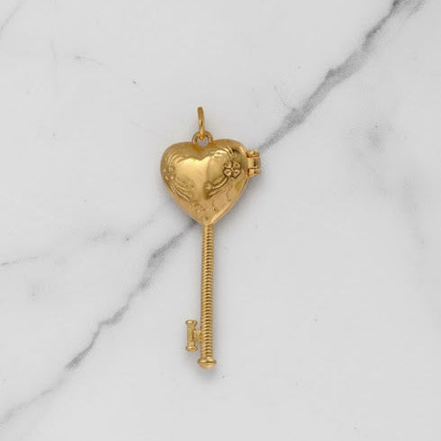 Gold key-shaped pendant on a marble background