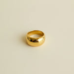 Gold ring with a white label on a light gray surface