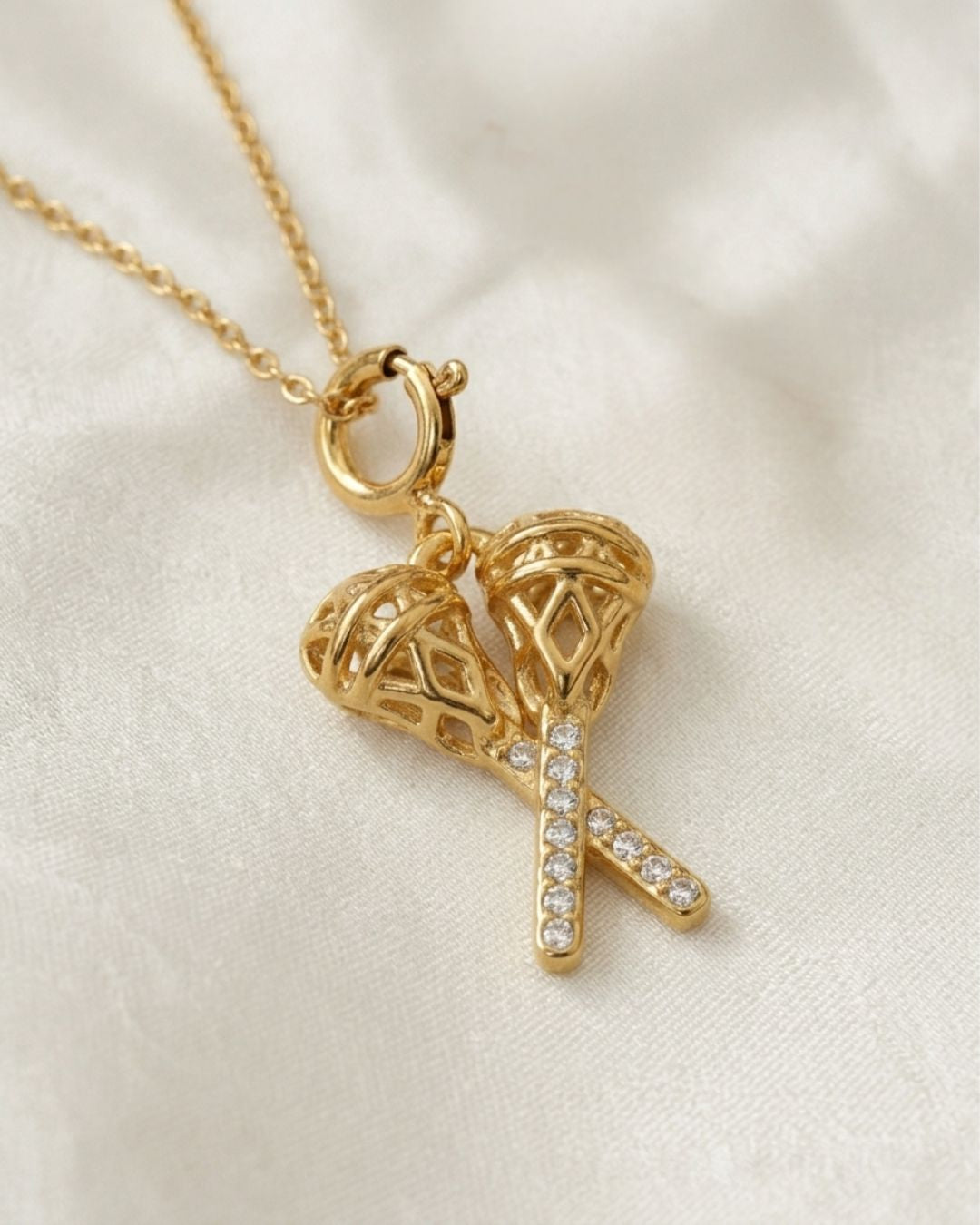 Gold necklace with heart and cross pendant on a beige fabric background