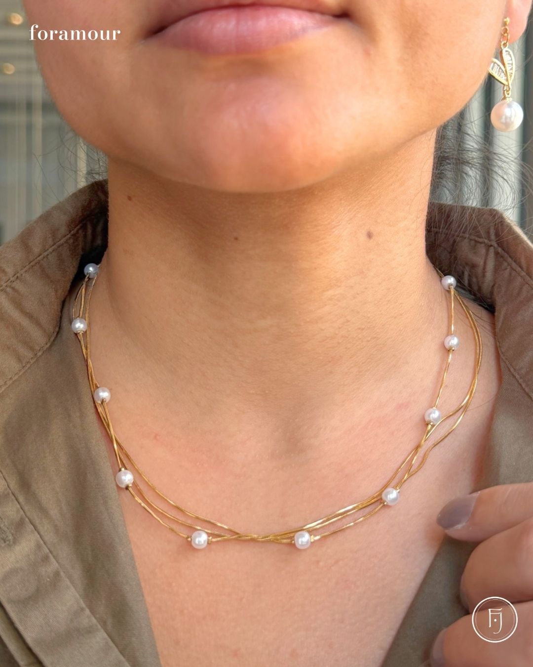 Close-up of a person wearing a gold necklace with pearl beads and matching earrings.