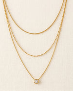 Two gold necklaces on a beige background