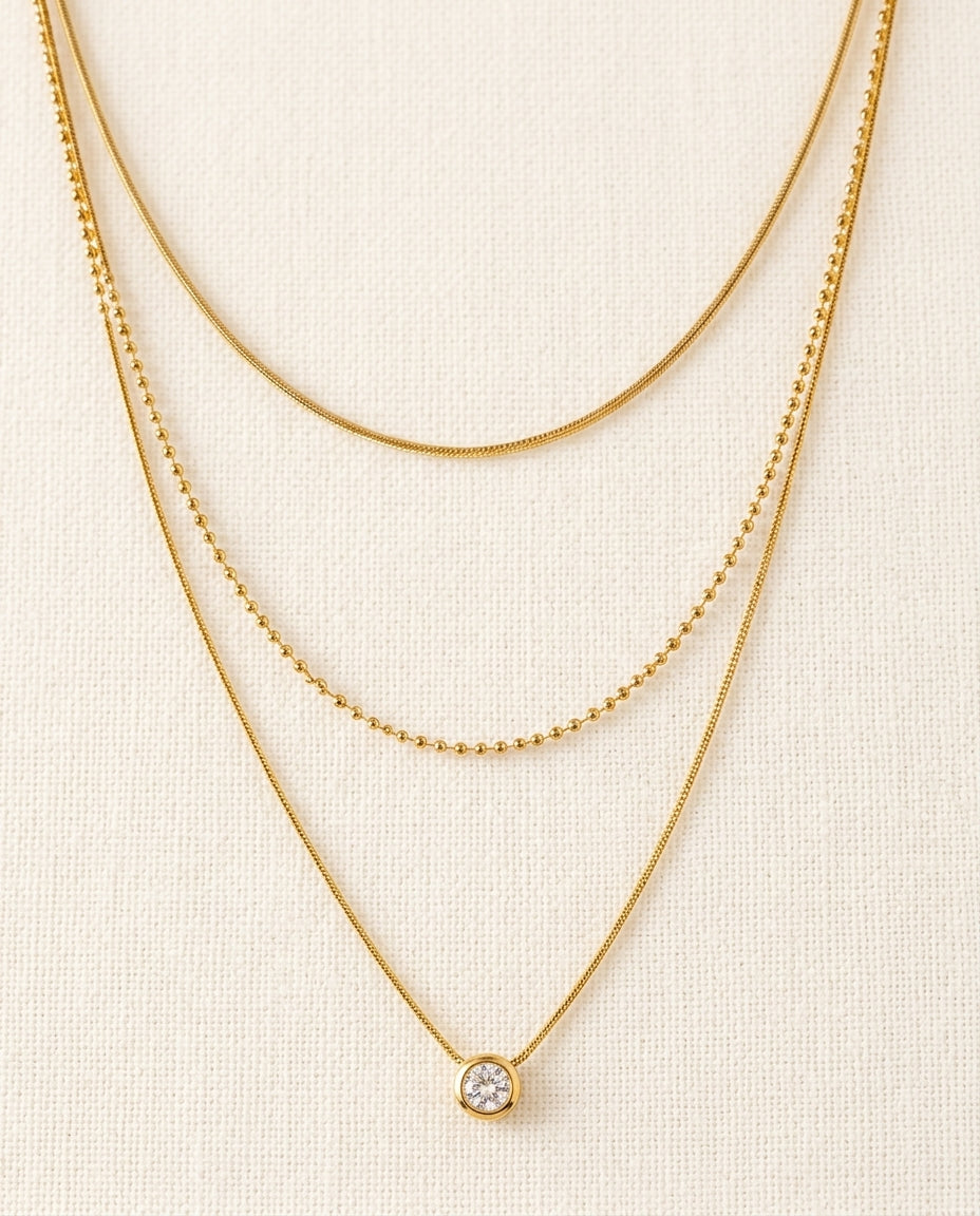 Two gold necklaces on a beige background