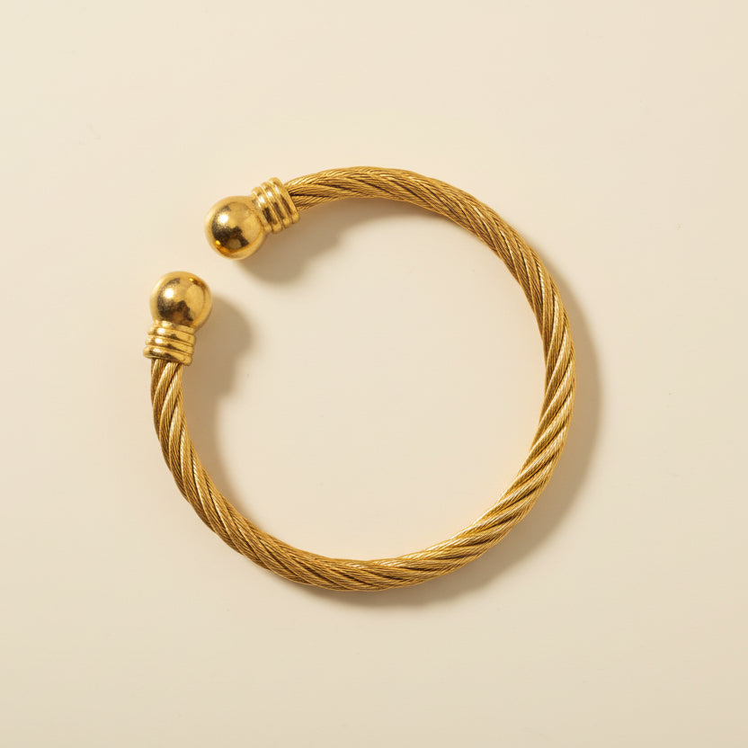 Gold bracelet on a light gray background