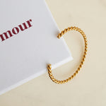 Gold twisted bracelet on a white card with 'foramour' branding
