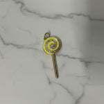 Key-shaped charm with a yellow circular design on a marble surface