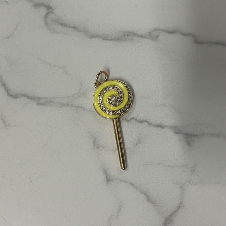Key-shaped charm with a yellow circular design on a marble surface