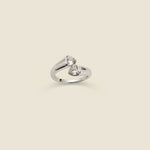 Silver ring with heart design on a beige cylindrical stand against a light background