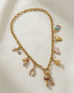 Gold charm bracelet with various charms on a white background
