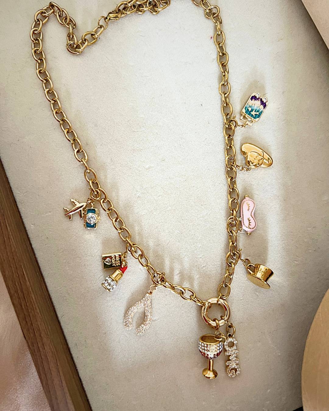 Gold necklace with various charms on a white stand