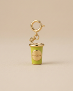 Green matcha cup charm with gold accents on a beige background