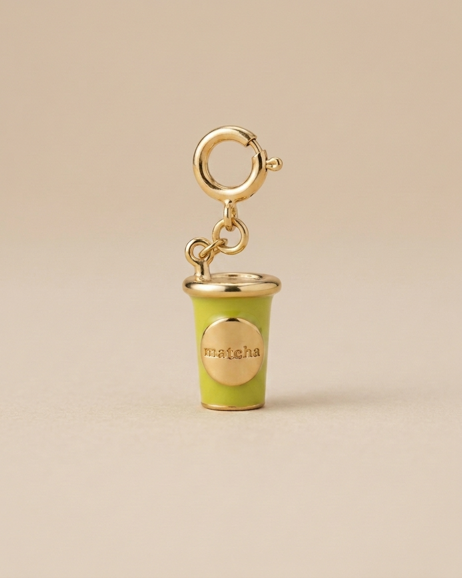 Green matcha cup charm with gold accents on a beige background