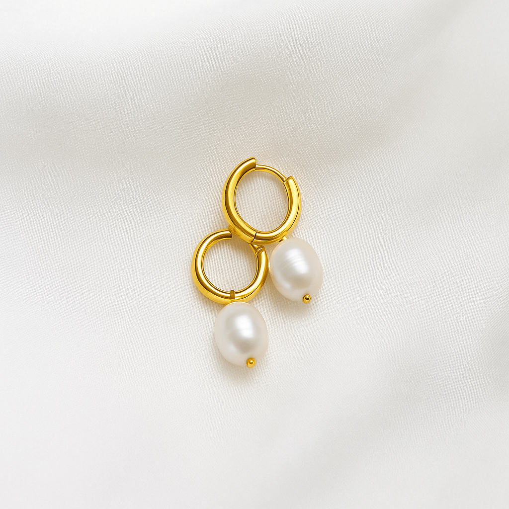 Gold hoop earrings with pearl drops on a light background
