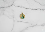 Gold pendant with green design on a marble background