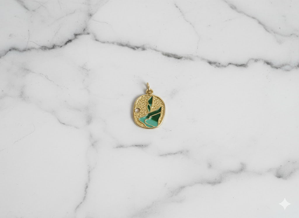 Gold pendant with green design on a marble background