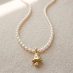 Pearl necklace with a gold pendant on a beige fabric background