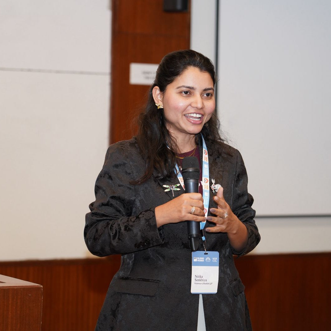 Woman holding a microphone and smiling in front of a screen