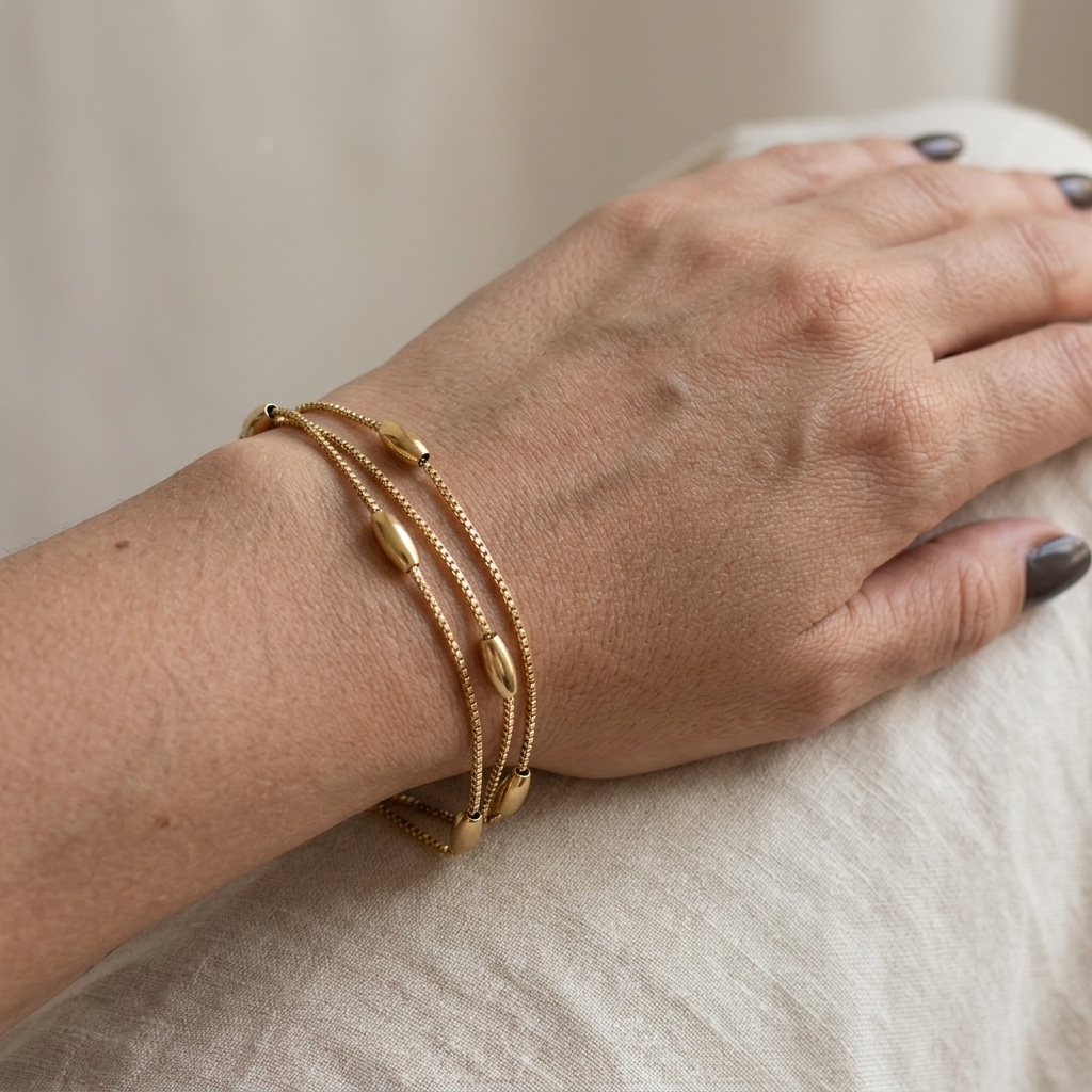 Gold bracelet on a wrist with a neutral background
