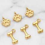 Gold paw print and bone charms on a marble background