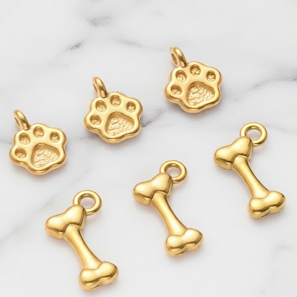 Gold paw print and bone charms on a marble background