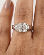 Pear-shaped diamond ring on a hand with a white background