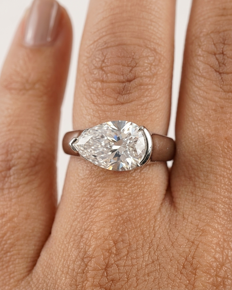 Pear-shaped diamond ring on a hand with a white background