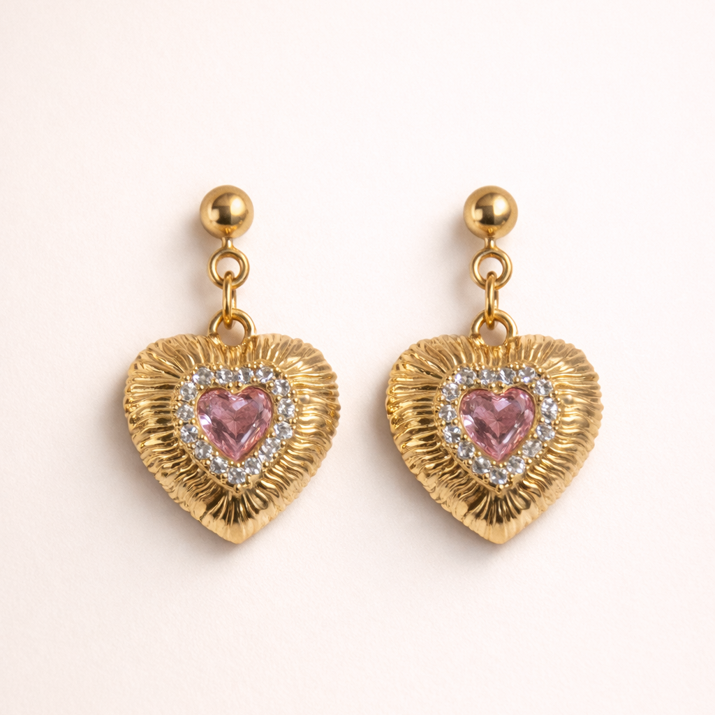 Heart-shaped earrings with pink gemstones and gold accents on a white background