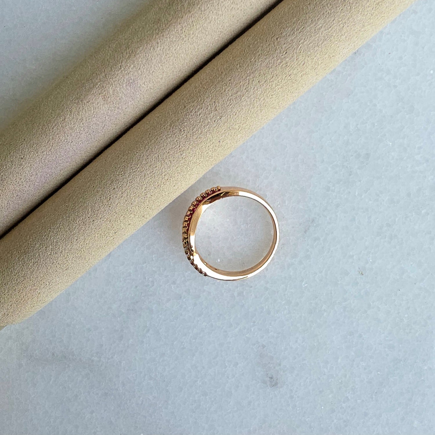 Gold ring on a textured beige and light gray surface