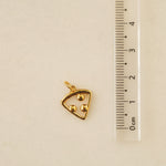 Gold triangular pendant on a gray background with a ruler for scale.
