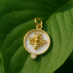 Gold pendant with bee design on a green leaf
