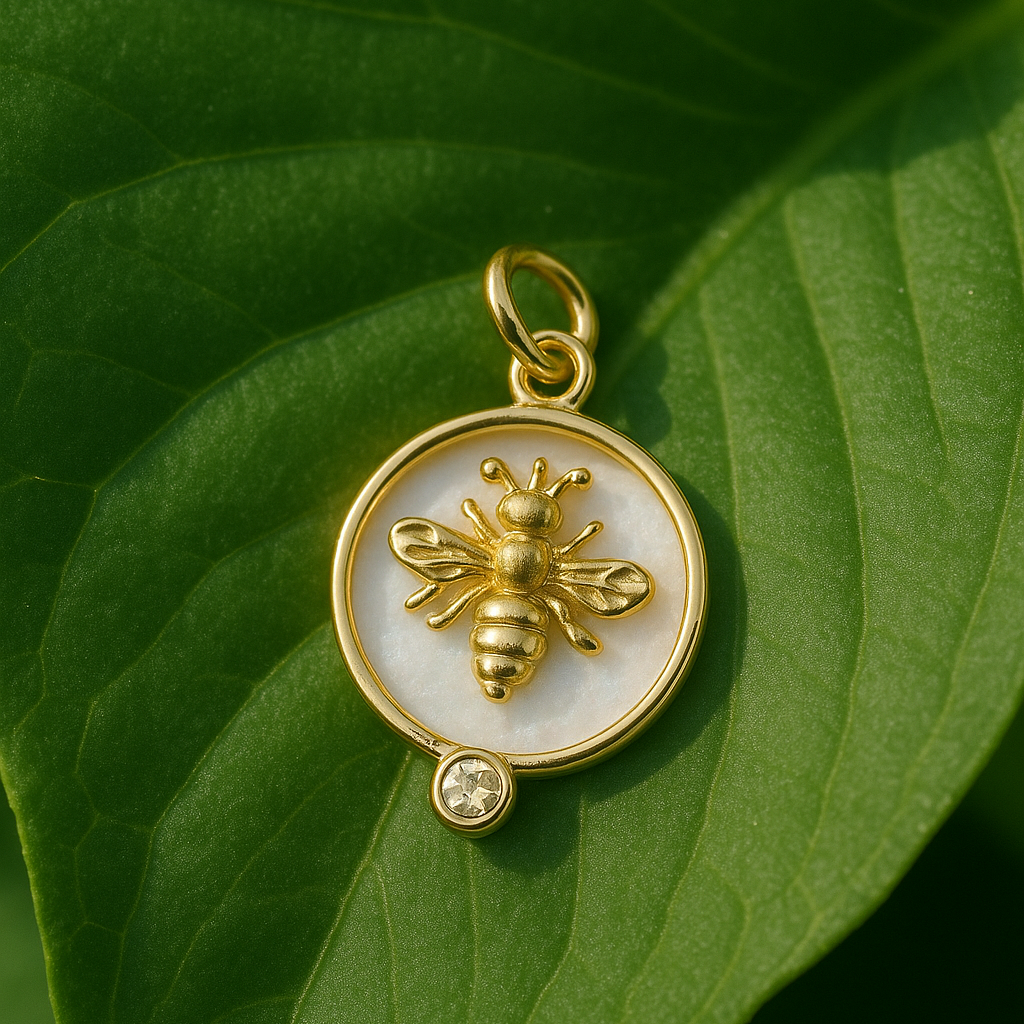 Gold pendant with bee design on a green leaf