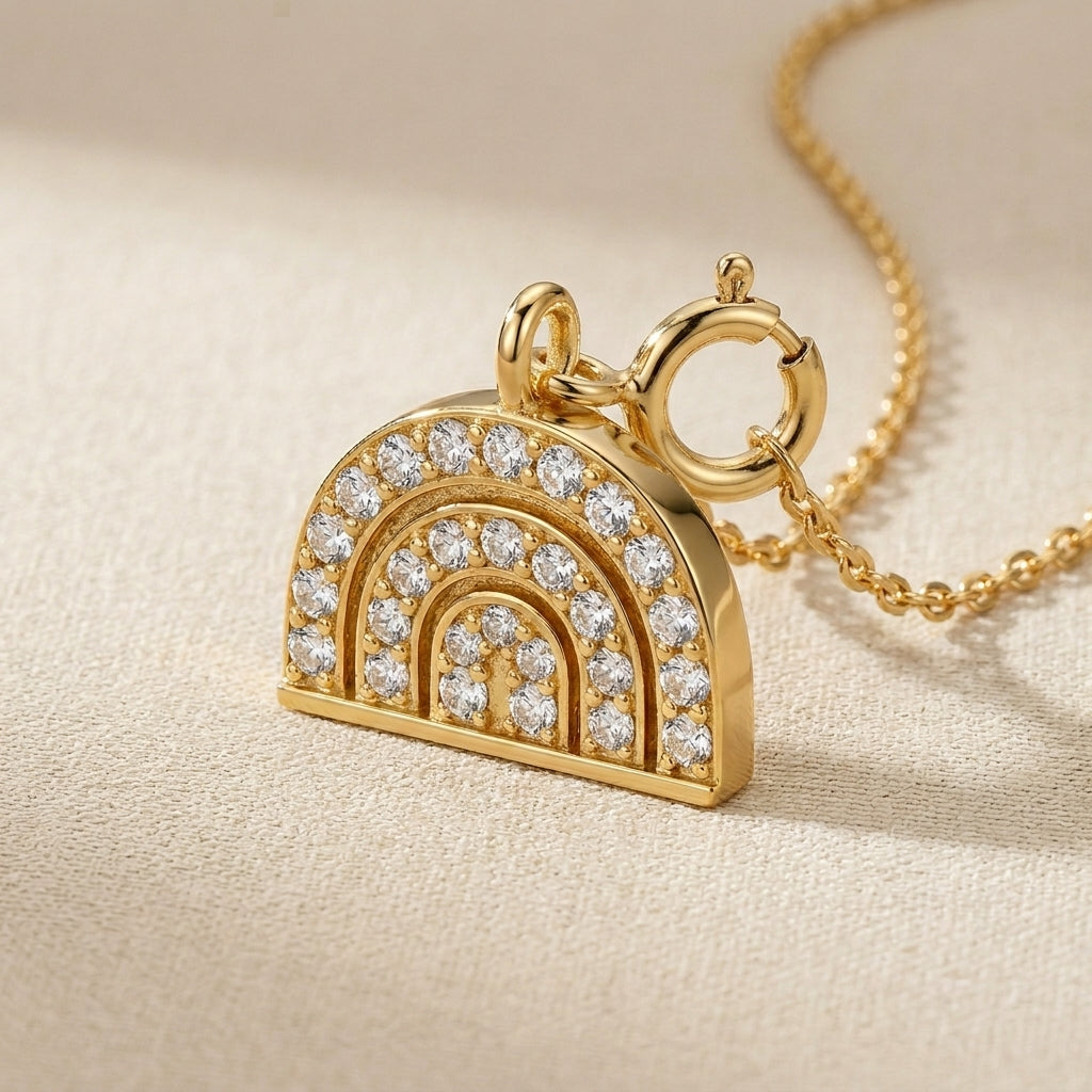 Gold rainbow-shaped pendant with diamonds on a beige background