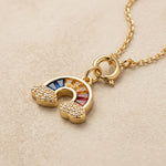 Gold necklace with a colorful pendant on a beige background