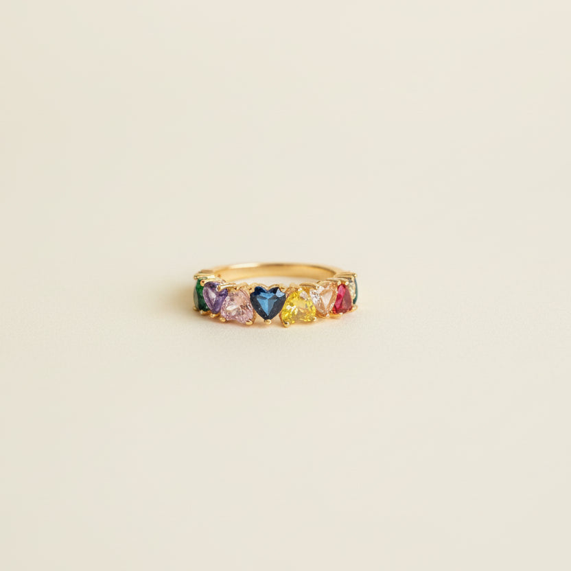 Ring with multicolored gemstones on a beige cylindrical object against a light background