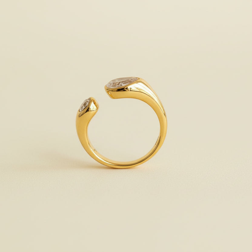 Gold ring with gemstones on a textured beige and light gray background