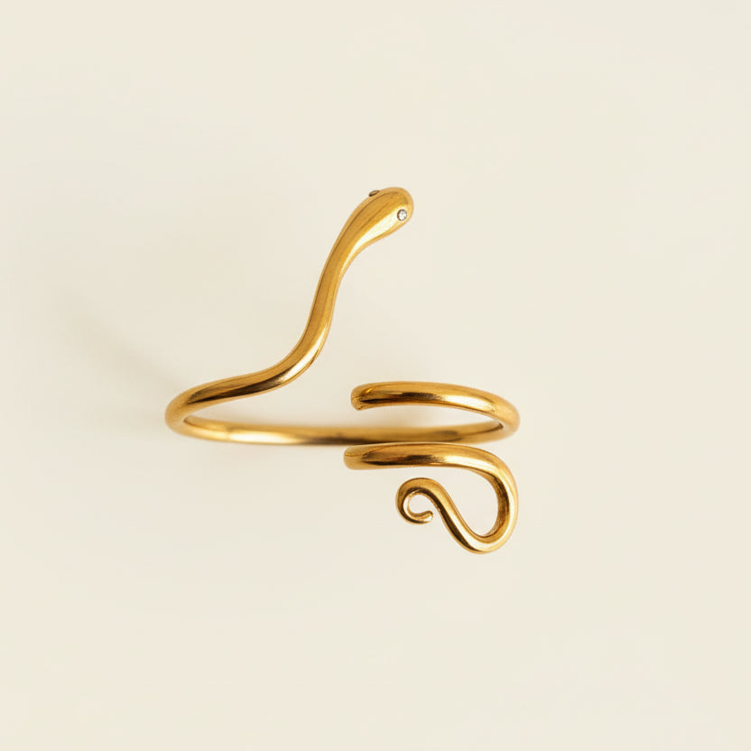 Gold snake-shaped ring on a light gray surface