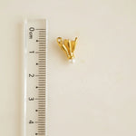 Gold earring on a gray background with a ruler for scale