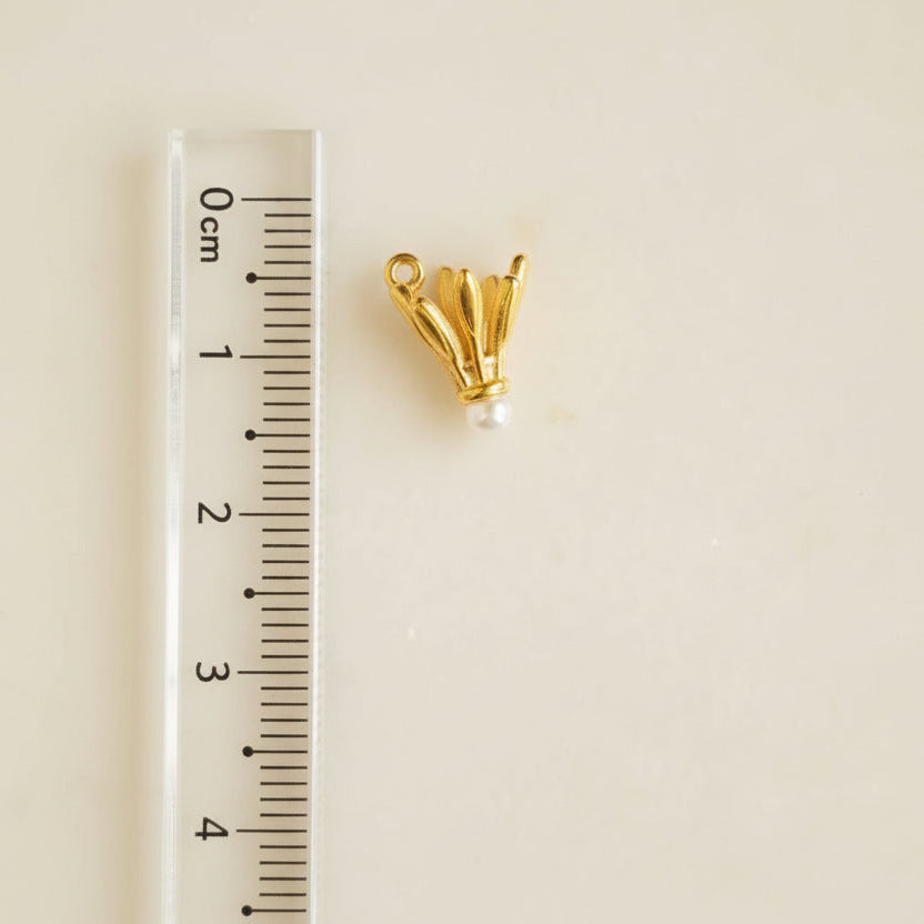 Gold earring on a gray background with a ruler for scale