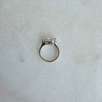 Silver ring with a diamond on a light gray marble surface