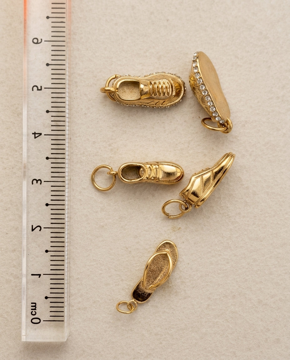 Gold jewelry clasps on a beige surface with a ruler for scale.