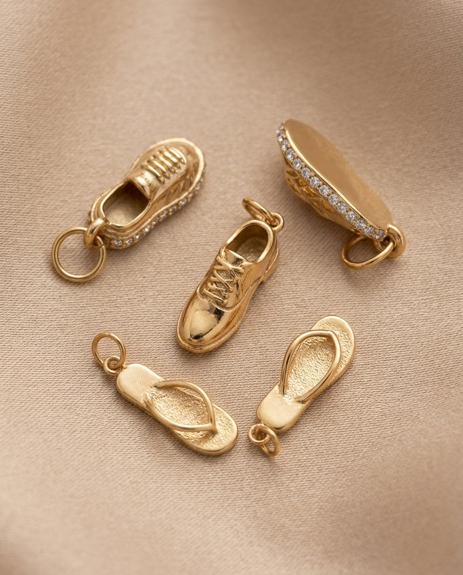 Gold shoe-shaped charms on a beige fabric background