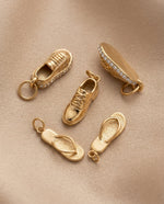 Gold shoe-shaped charms on a beige fabric background