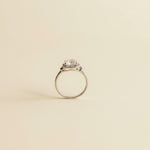 Silver ring with a diamond on a light gray marble surface