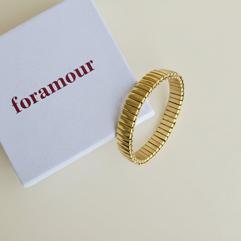 Gold bracelet on a white card with 'foramour' text on a marble surface