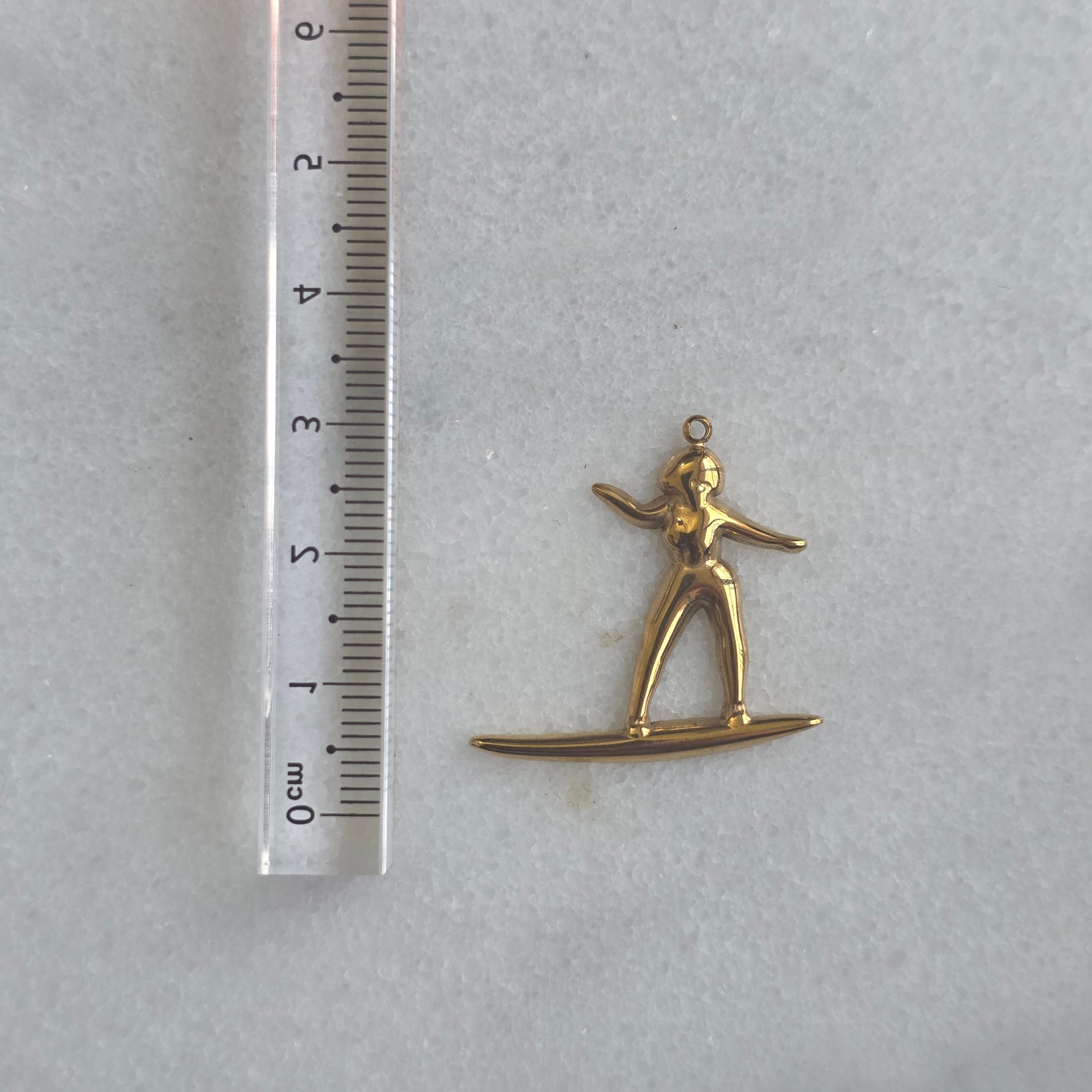 Gold pendant of a person on skis on a marble background