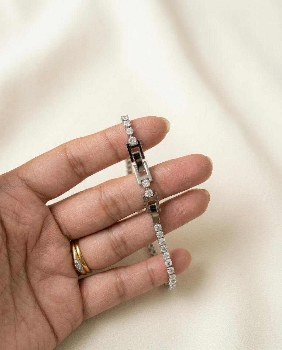 Silver bracelet on a hand with a plain background