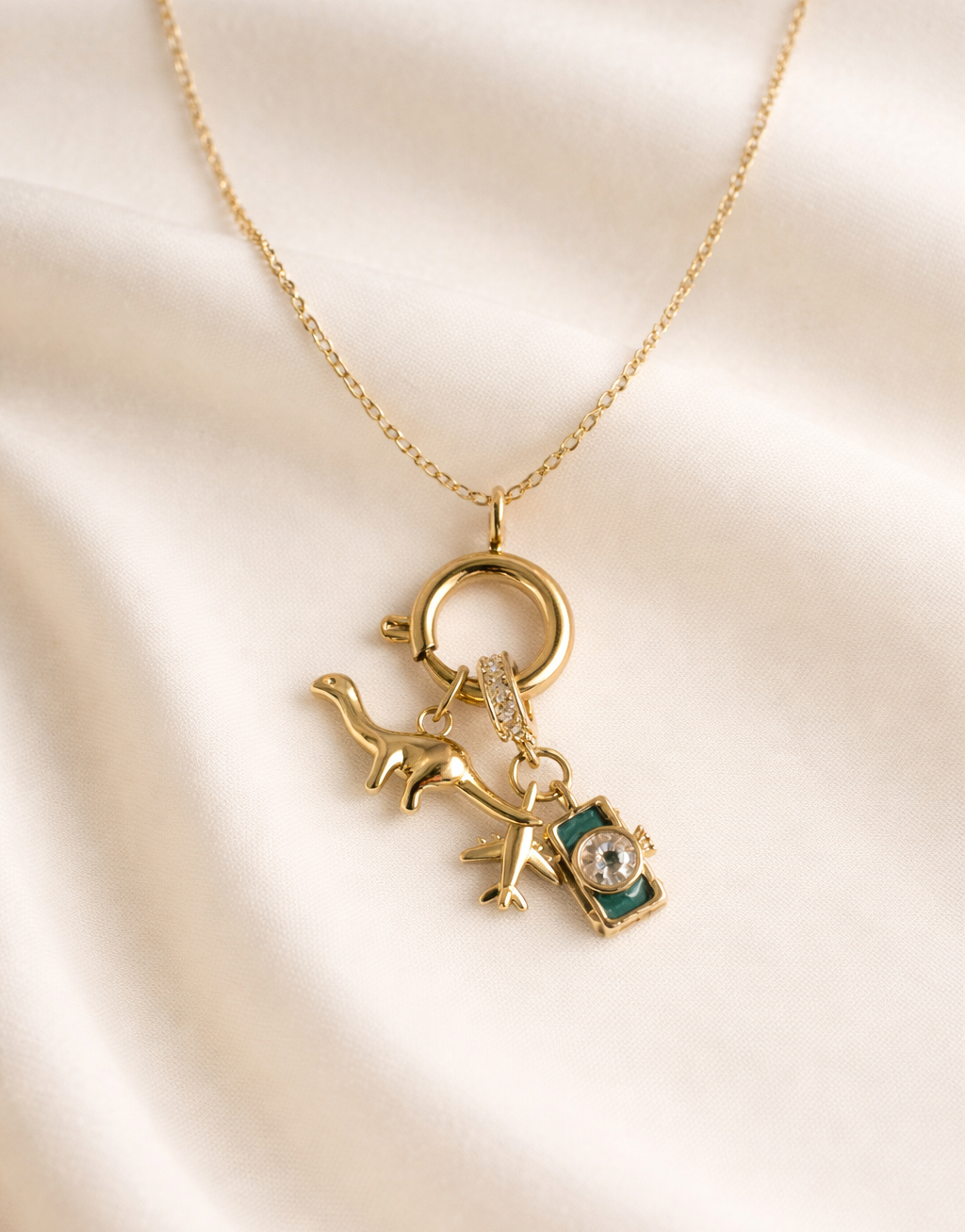 Gold necklace with a DIANASOUR charm on a beige fabric background