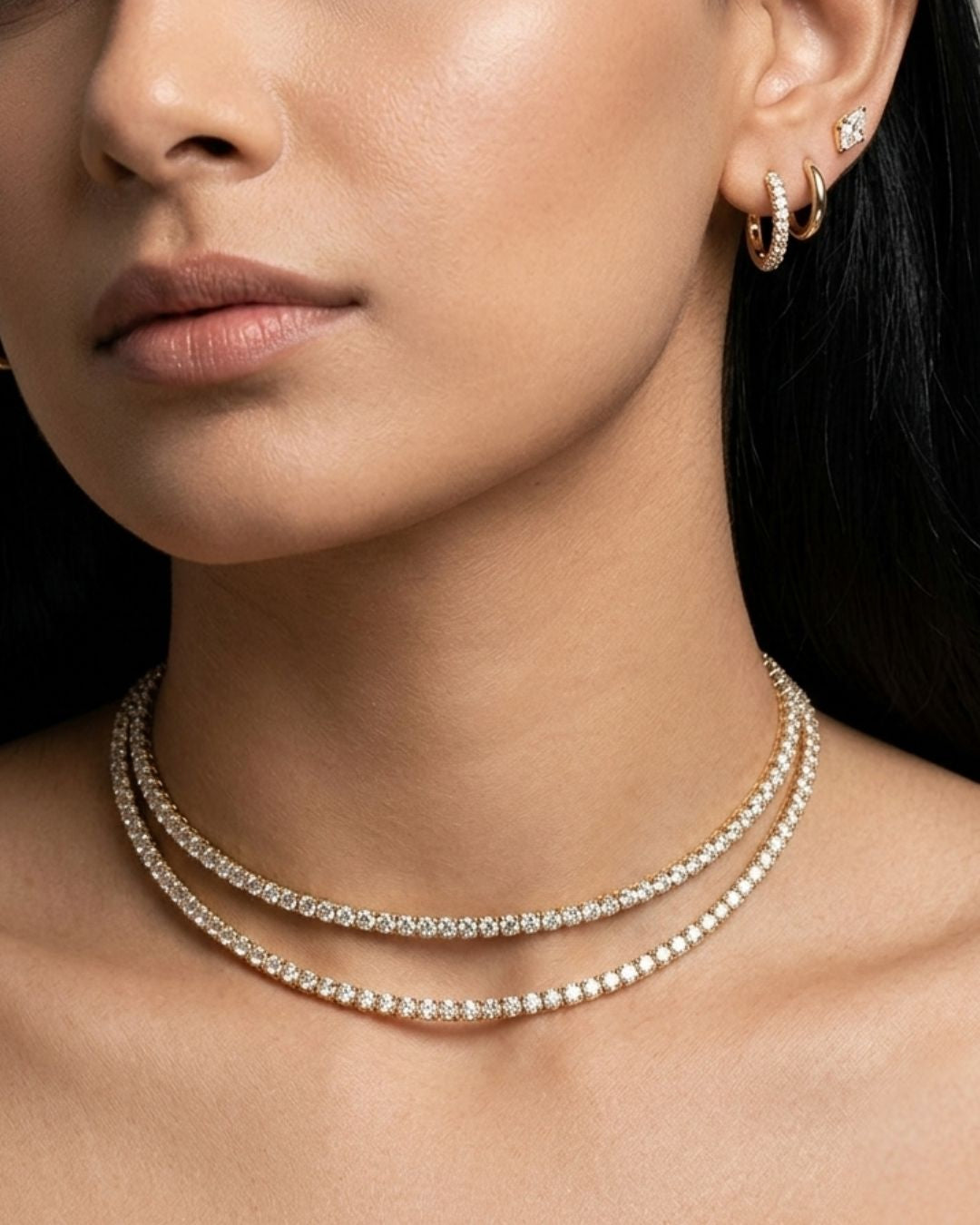 Close-up of a person wearing a silver necklace and gold hoop earrings.
