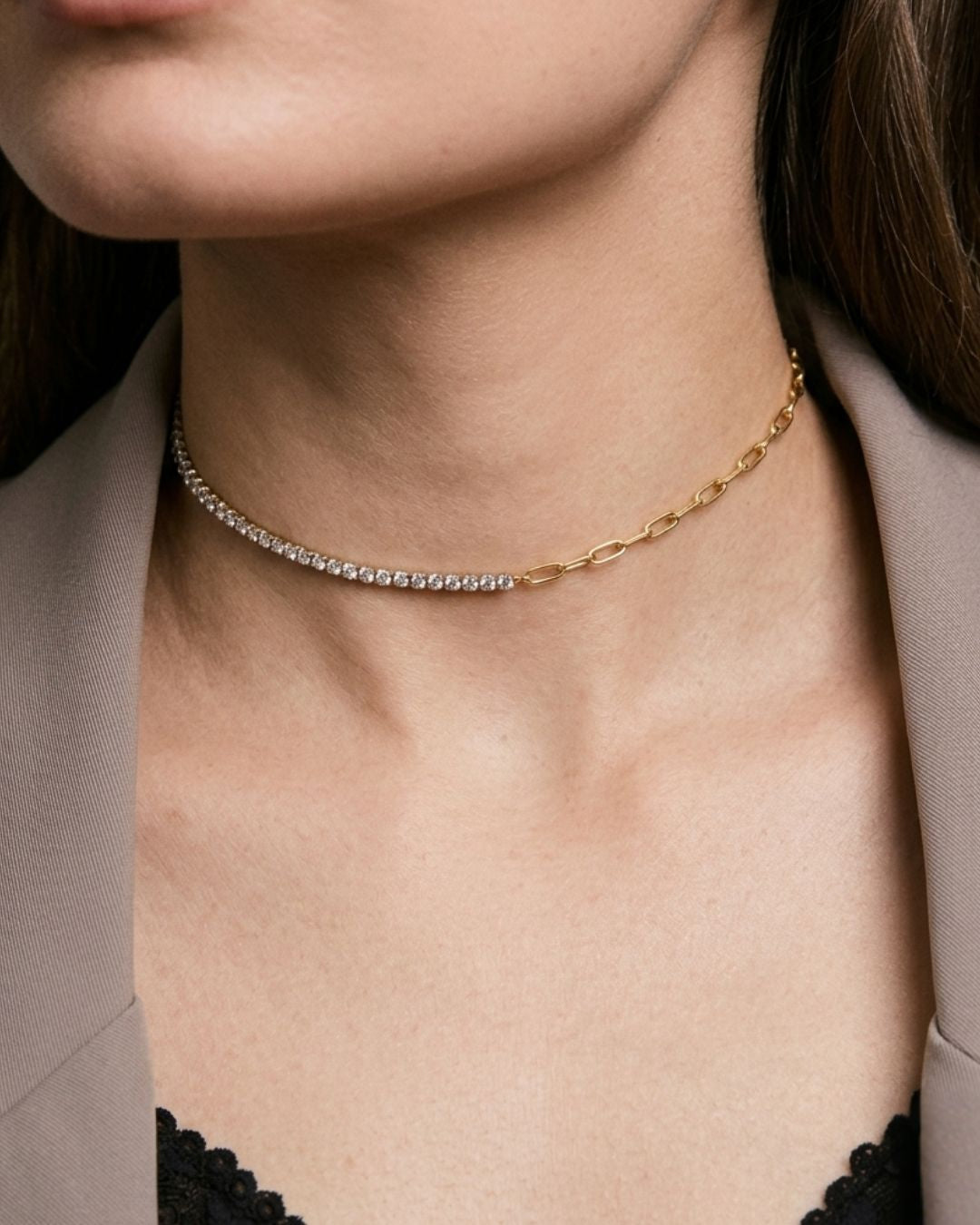 Close-up of a person wearing a gold necklace with a neutral background