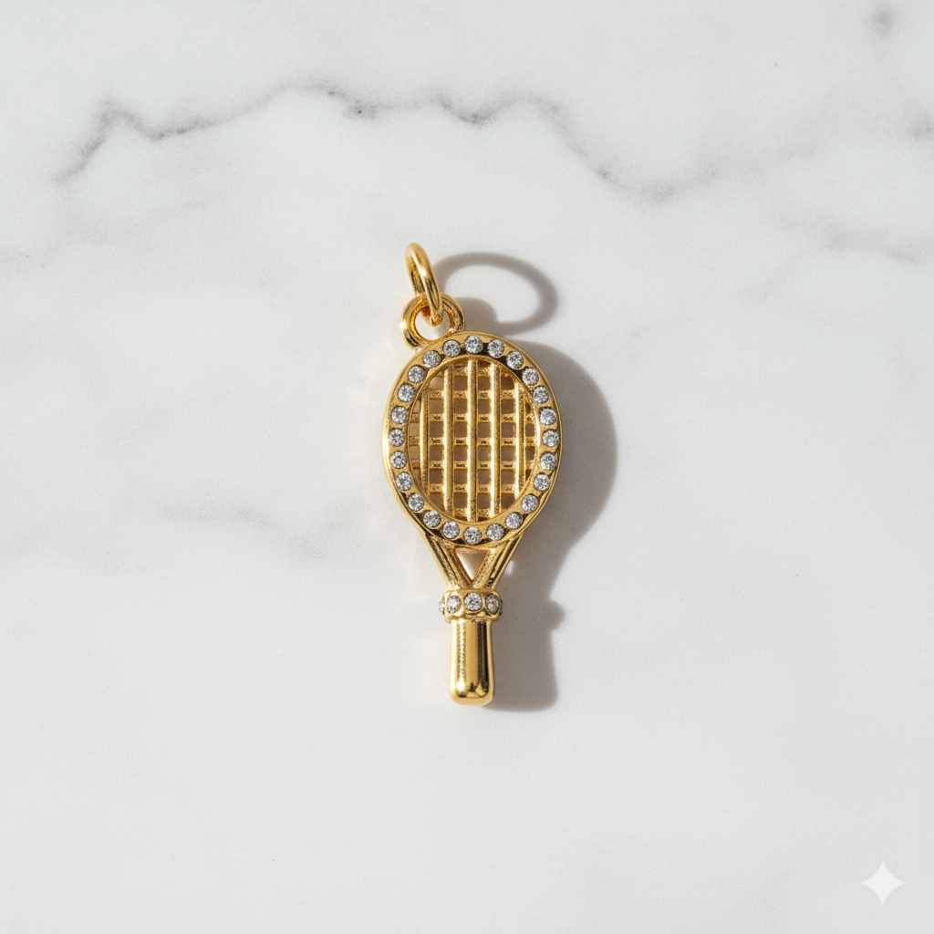 Gold tennis racket charm with rhinestones on a marble background